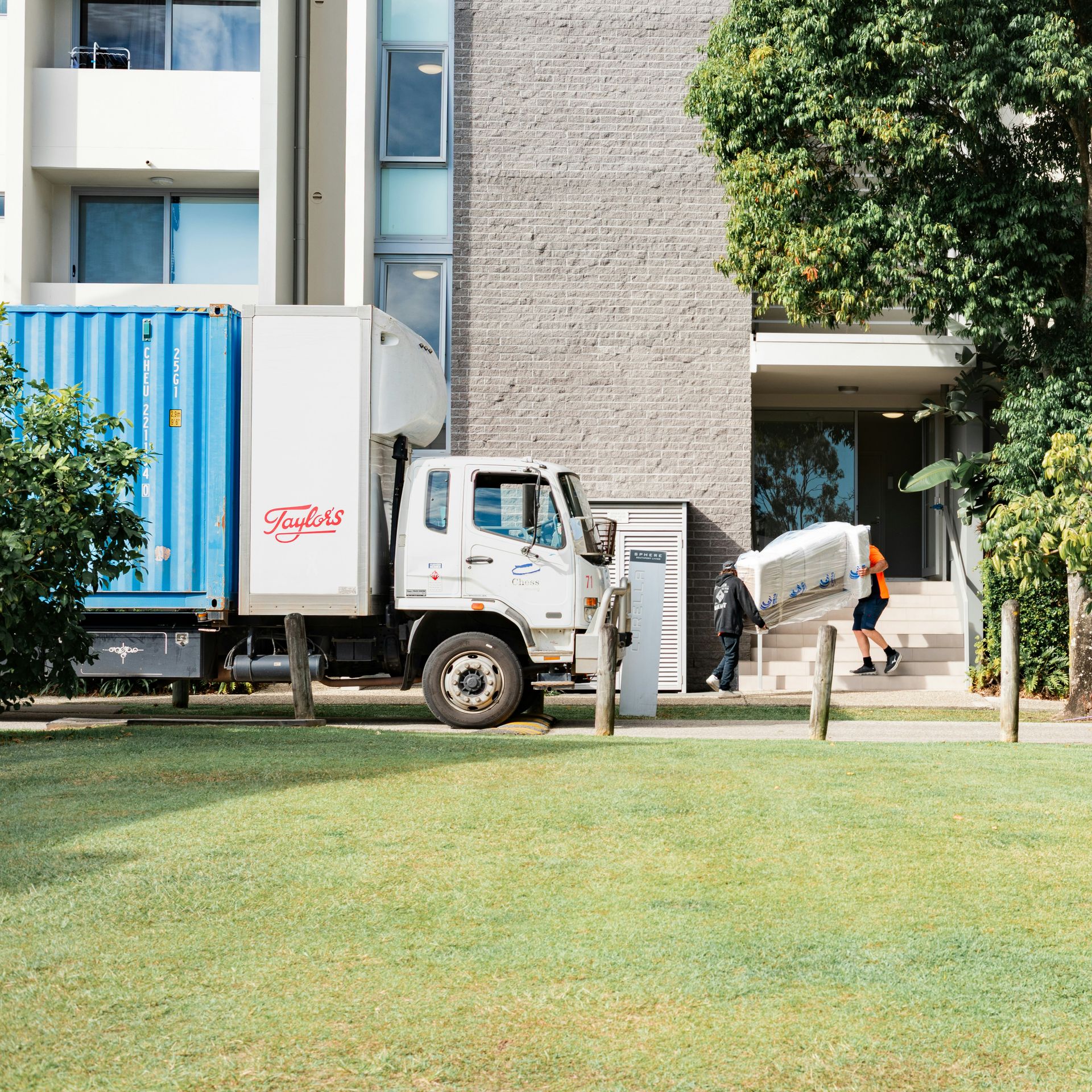 Moving truck and person carrying furniture near a building